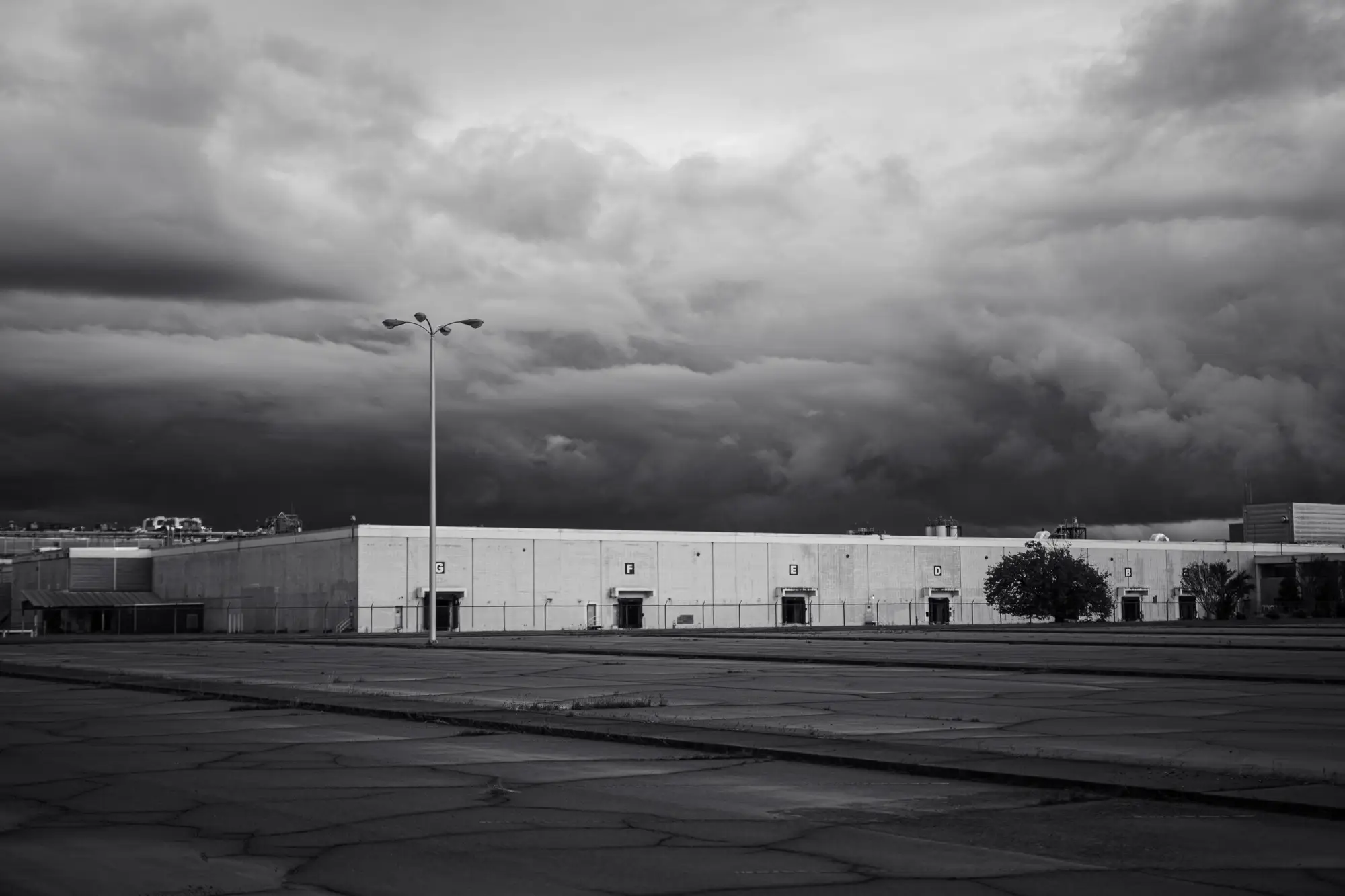 A distribution warehouse and empty yard under a dark storm front